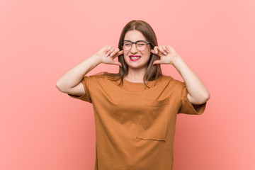 Young student woman wearing eyeglasses covering ears with hands.