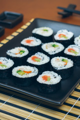 Sushi maki rolls presented on a tray with sauces and chopsticks