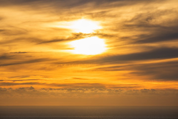 Dramatic golden rays sunset or sunrise with clouds over the ocean.