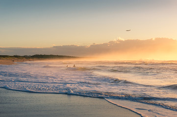 Ocean coastline with unrecognizable people at sunset