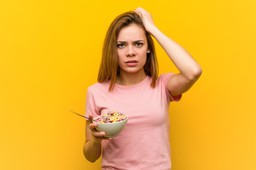Young woman holding a cereals bowl being shocked, she has remembered important meeting.