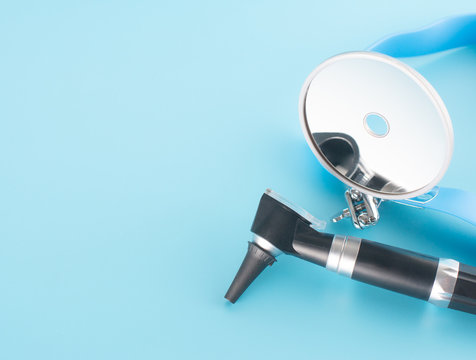 Otoscope with reflector mirror on blue background in health care concept.