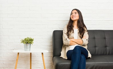 Young arab woman sitting on the sofa smiling confident with crossed arms.