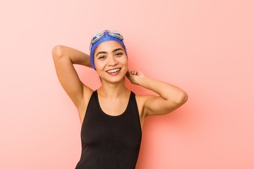 Young arab swimmer woman isolated stretching arms, relaxed position.