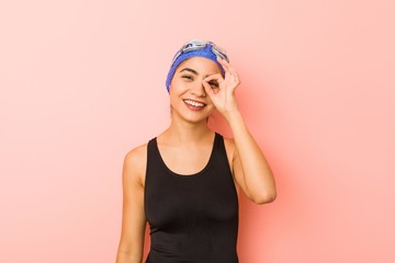 Young arab swimmer woman isolated excited keeping ok gesture on eye.