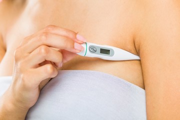 Close up of a young arab woman measuring her body temperature