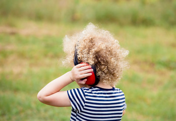Young child wearing noise blocking headphones at outdoor concert, preventing hearing loss at young...
