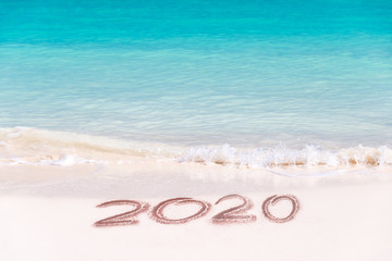 Fototapeta na wymiar 2020 written on the sand of a beach, travel and holidays 2020 new year concept