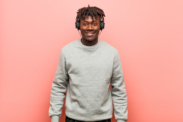 Young rasta black man listening to music with headphones happy, smiling and cheerful.