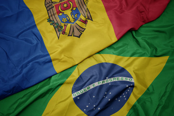 waving colorful flag of brazil and national flag of moldova.