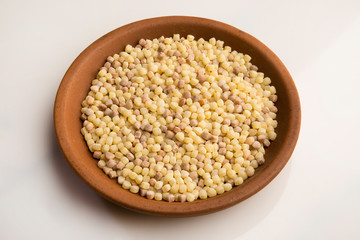 Fregola nel piatto di terracotta sfondo bianco