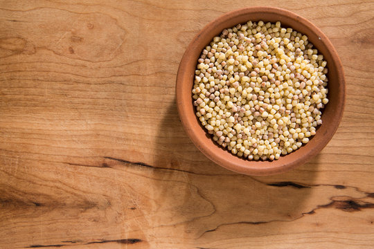 Fregola nel piatto di terracotta sfondo bianco