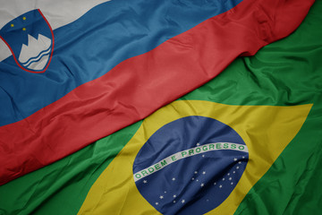 waving colorful flag of brazil and national flag of slovenia.