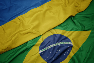 waving colorful flag of brazil and national flag of ukraine.