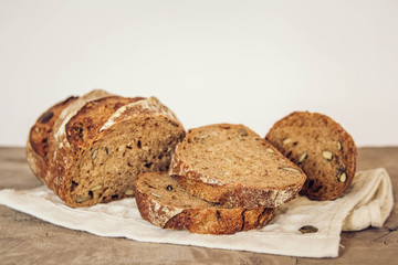 Brown fresh bread with seeds are cut into pieces on old wood background. Top view, copy space