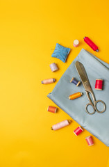 Composition of sewing accessories on a colored yellow background top view.