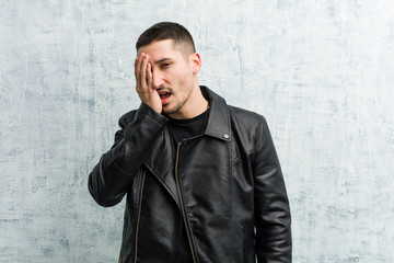 Young rocker man having fun covering half of face with palm.