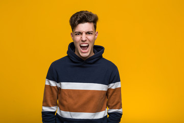 Young cool man wearing a hoodie screaming very angry and aggressive.