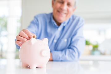 Man putting a coin inside piggy bank as savings smiling confident