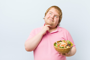 Caucasian crazy blond fat man holding a salad bowl