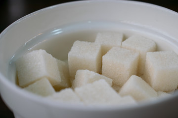 Refined sugar cubes in a sugar bowl.