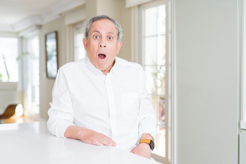 Fototapeta premium Handsome senior man at home afraid and shocked with surprise expression, fear and excited face.