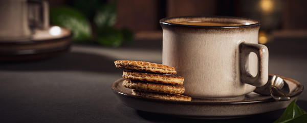 Cafe background with brown cup of coffee and dutch traditional cookies stroopwafels. Retro style toned. Banner.
