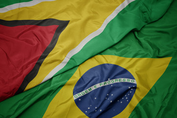 waving colorful flag of brazil and national flag of guyana.