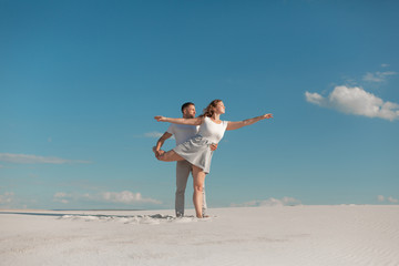 Fototapeta na wymiar Romantic couple dancing in sand desert at blue sky background