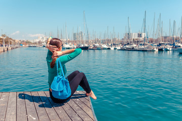 Tourist woman in the port of Barcelona, Catalonia, Spain. Scenic seascape of marina and sailboats yachts. Public promenade and famous tourist destination near La Ramblaa street