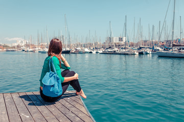 Tourist woman in the port of Barcelona, Catalonia, Spain. Scenic seascape of marina and sailboats yachts. Public promenade and famous tourist destination near La Ramblaa street
