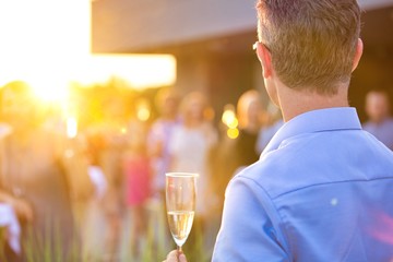 Mature businessman toasting wineglass with colleagues during success party on rooftop