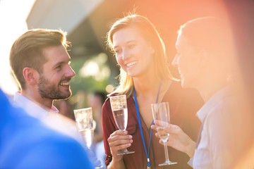 Young business colleagues talking while standing at success party on rooftop