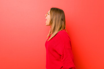 Young authentic charismatic real people woman against a wall shouting towards a copy space