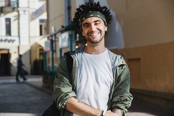 Smiling handsome man, happy hipster guy with dreadlocks hairstyle posing outdoor in the city...