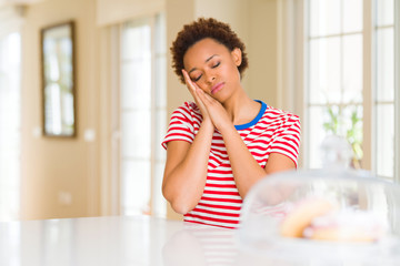 Young beautiful african american woman at home sleeping tired dreaming and posing with hands together while smiling with closed eyes.