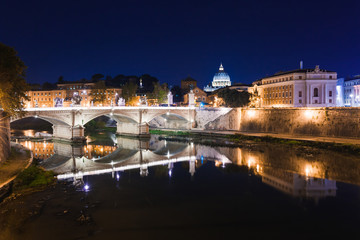 Fototapeta na wymiar Cityscape romantic night view of Roma. Panorama with Saint Peter's basilica and Saint Angelo castle and bridge. Famous tourist destination with Tiber. Travel illuminated landscape in Italy, Europe.