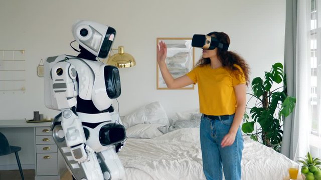 A lady in VR-glasses is touching a human-like robot. Robot, human like cyborg concept.