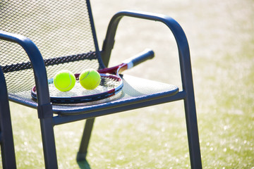 Tennis racket and ball on chair at court
