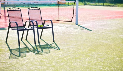 Tennis racket and ball on chair against court