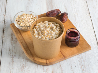 Oatmeal porridge with dates in a cardboard cup. Healthy food and diet concept.