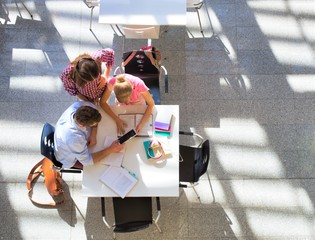 Students doing group projects while sitting on table at university library