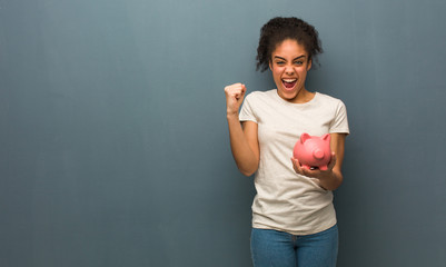 Young black woman screaming very angry and aggressive. She is holding a piggy bank.