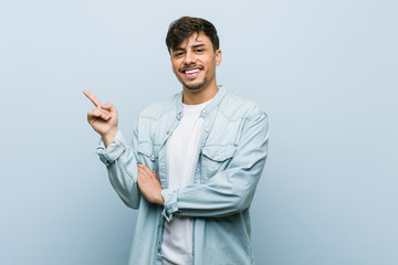 Young hispanic cool man smiling cheerfully pointing with forefinger away.