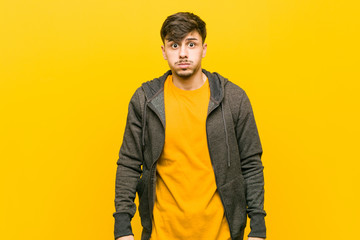 Young hispanic casual man blows cheeks, has tired expression. Facial expression concept.