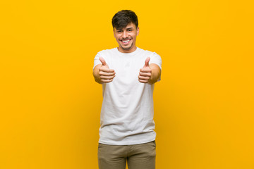 Young hispanic casual man with thumbs ups, cheers about something, support and respect concept.