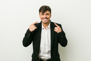 Young business hispanic man smiles, pointing fingers at mouth.