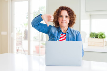 Senior woman working using computer laptop with angry face, negative sign showing dislike with thumbs down, rejection concept