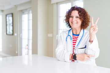 Senior doctor woman wearing medical robe at the clinic smiling with happy face winking at the...