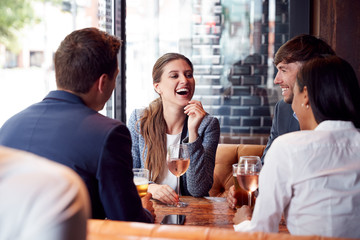 Group Of Business Colleagues Meeting For Drinks And Socializing In Bar After Work